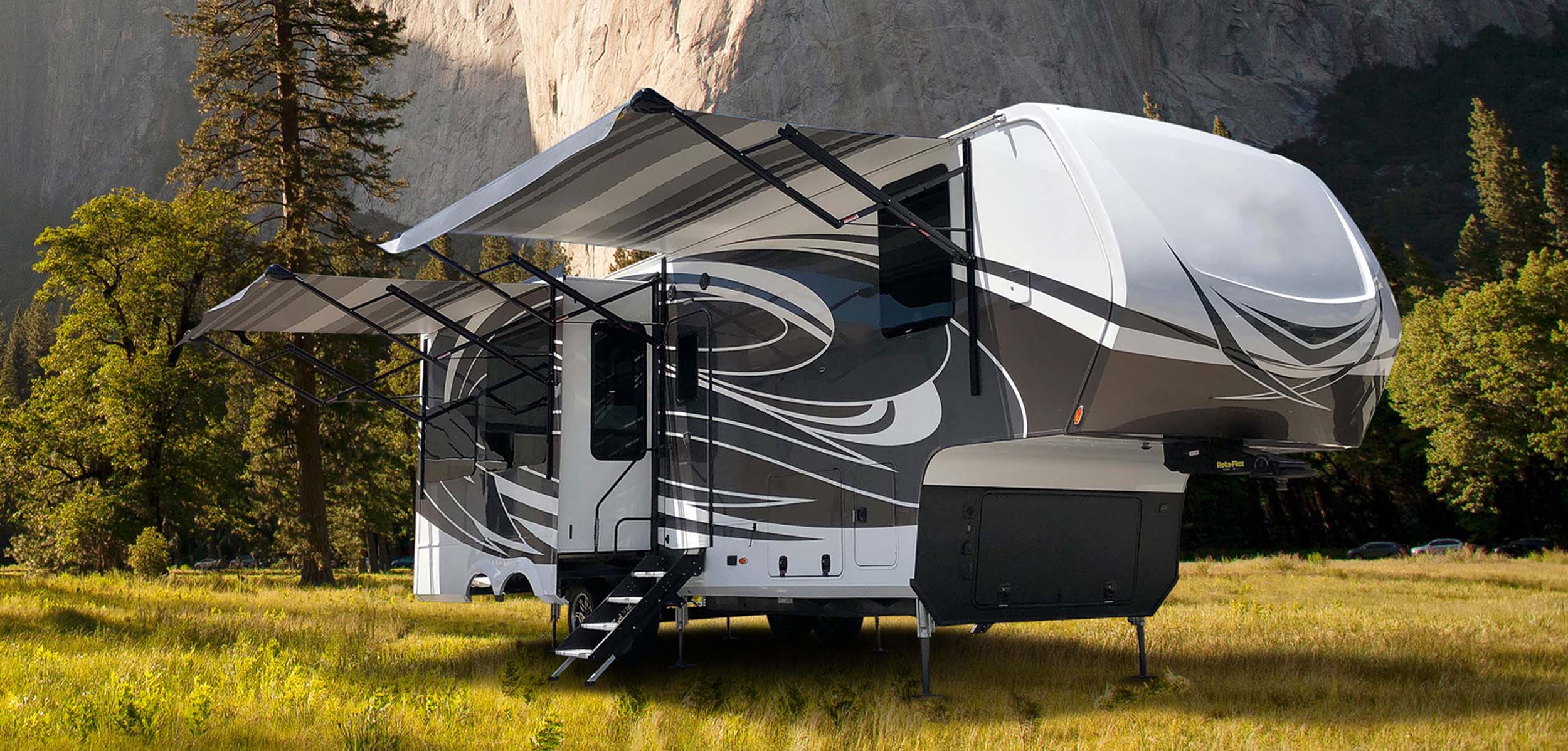 Fifth-wheel RV with awning extended in a mountain meadow
