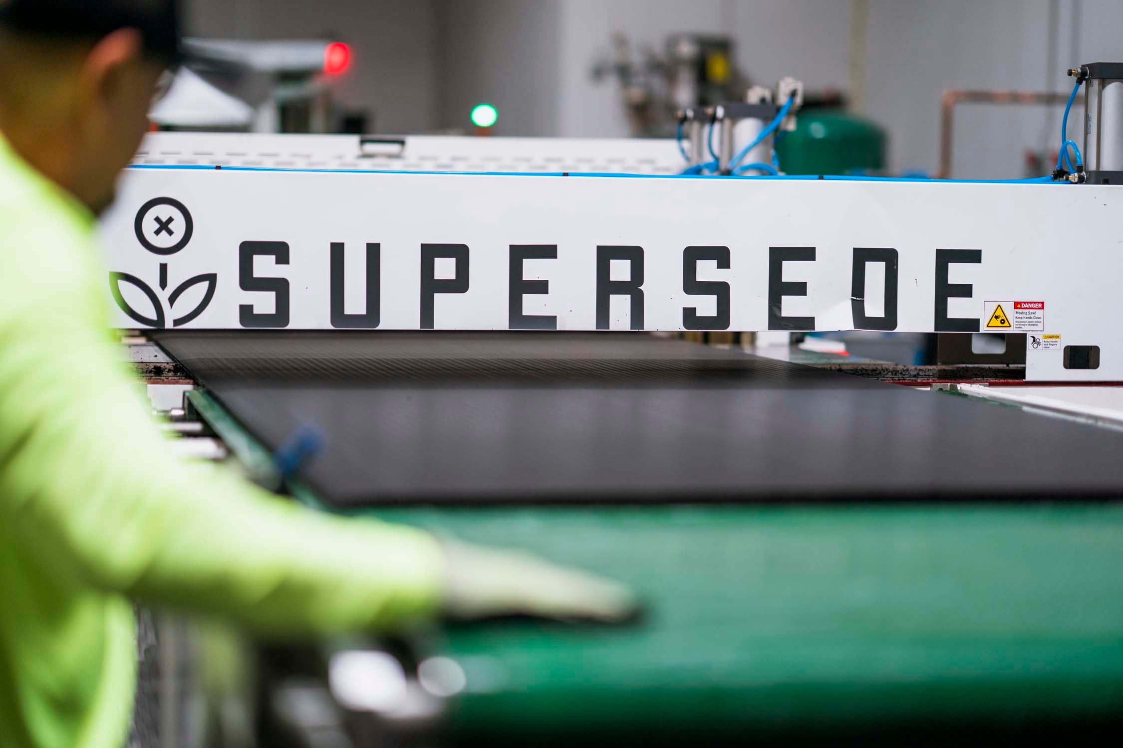 A worker guiding a Supersede Marine Board panel through the branded production line